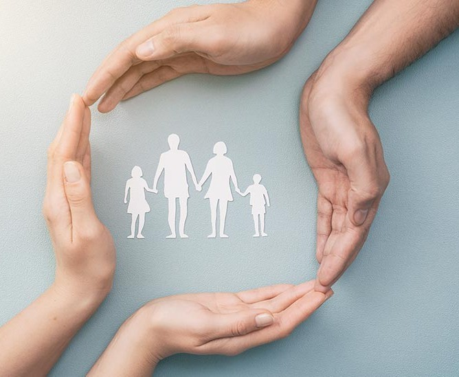 Hands cradling a paper cut-out of a family